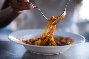 Image showing a young African American woman eating pasta