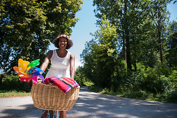 Image showing pretty young african american woman riding a bike in forest