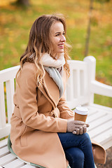 Image showing happy young woman drinking coffee in autumn park