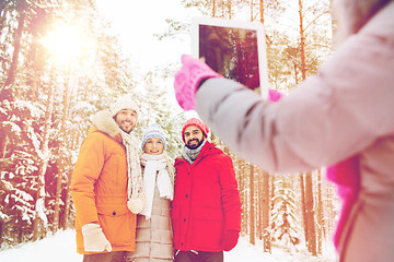 Image showing smiling friends with tablet pc in winter forest