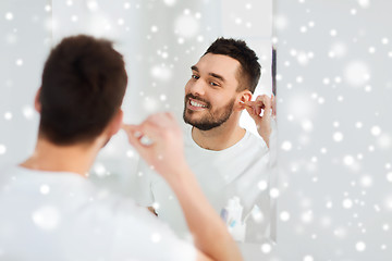 Image showing man cleaning ear with cotton swab at bathroom