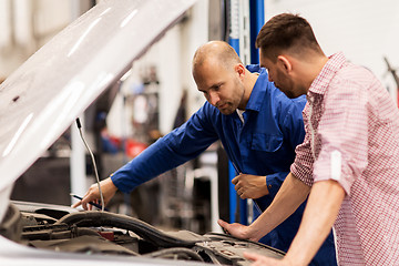 Image showing auto mechanic with clipboard and man at car shop