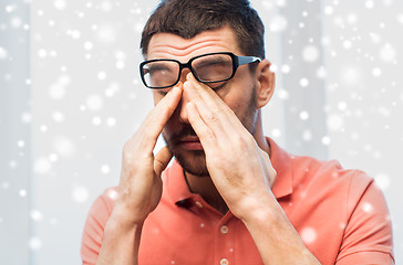Image showing tired man in eyeglasses rubbing eyes at home