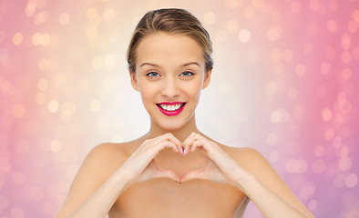 Image showing smiling young woman showing heart shape hand sign