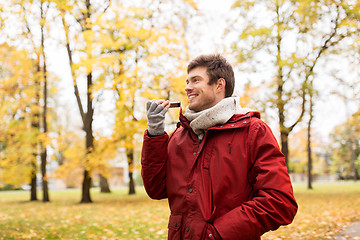 Image showing man recording voice on smartphone at autumn park