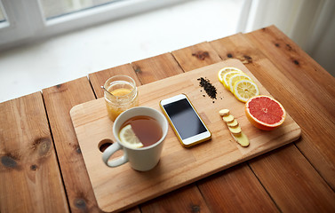 Image showing smartphone with cup of lemon tea, honey and ginger