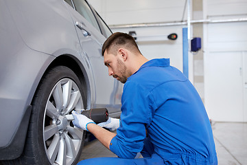 Image showing mechanic with screwdriver changing car tire