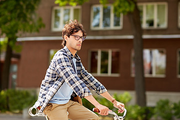 Image showing young hipster man with bag riding fixed gear bike