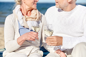 Image showing happy senior couple drinking wine on summer beach