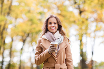 Image showing happy young woman drinking coffee in autumn park