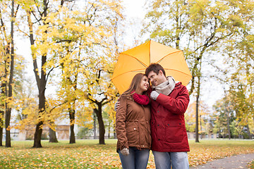 Image showing smiling couple with umbrella in autumn park