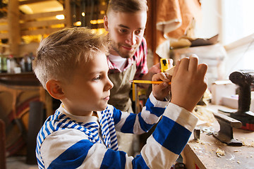 Image showing father and son with ruler measure wood at workshop