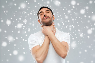 Image showing young man choking himself over snow background