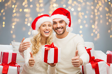 Image showing happy couple with christmas gifts and thumbs up