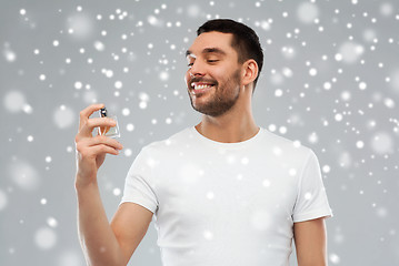 Image showing smiling man with male perfume over snow background