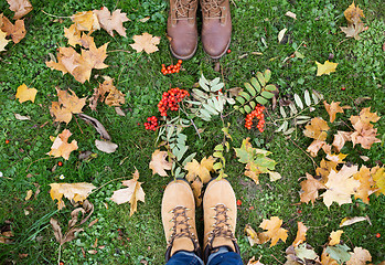 Image showing feet in boots with rowanberries and autumn leaves
