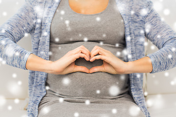 Image showing close up of happy pregnant woman making heart