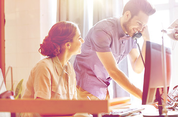 Image showing happy creative team calling on phone in office