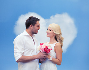 Image showing happy couple with flowers over heart shaped cloud