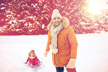 Image showing happy man carrying little kid on sled in winter