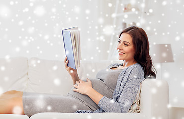 Image showing happy pregnant woman reading book at home