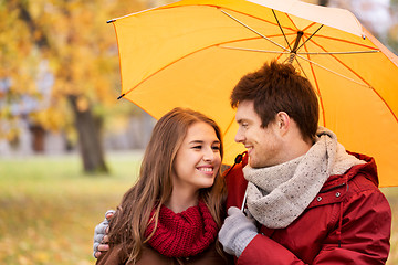 Image showing smiling couple with umbrella in autumn park