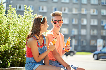 Image showing happy teenage couple eating hot dogs in city