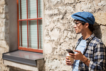 Image showing man with smartphone drinking coffee on city street