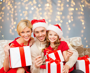 Image showing happy family holding gift boxes and sparkles