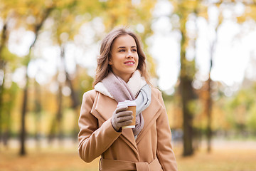 Image showing happy young woman drinking coffee in autumn park