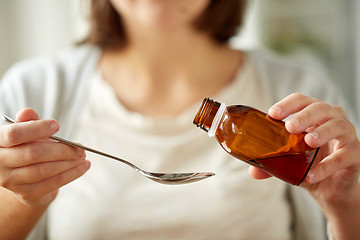 Image showing woman pouring medication from bottle to spoon