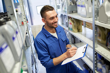 Image showing smiling auto mechanic with clipboard at car shop