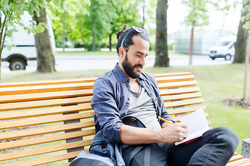 Image showing man writing to notebook or diary on city street