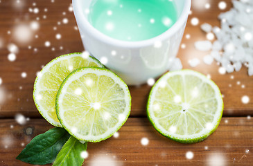 Image showing citrus body lotion in cup and limes on wood