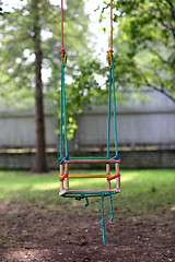 Image showing empty wooden swing hanging in summer garden