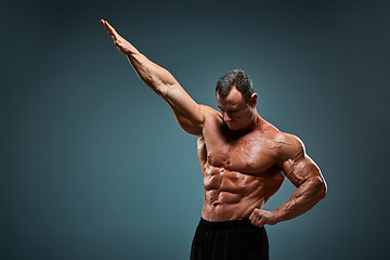 Image showing torso of attractive male body builder on gray background.