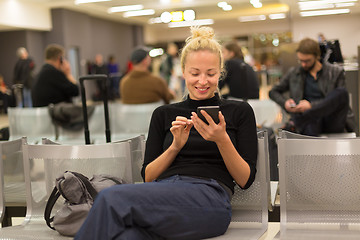 Image showing Lady using smart phone while waiting at airpot departure gates.