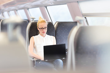 Image showing Woman travelling by train working on laptop.