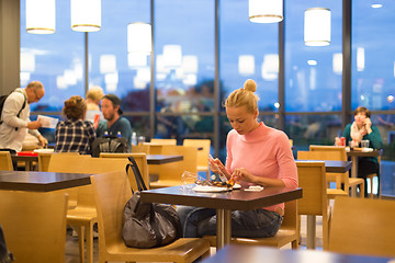 Image showing Young woman eating pizza at airport restaurant while waiting for flight departure.