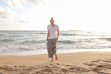 Image showing Woman walking on sand beach at golden hour