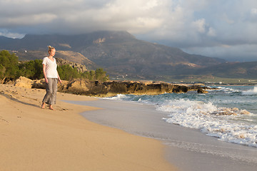 Image showing Woman walking on sand beach at golden hour