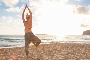 Image showing Woman practicing yoga on sea beach at sunset.