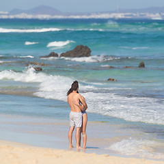 Image showing Young couple embracing on sandy beach.