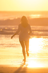 Image showing Woman running on the beach in sunset.