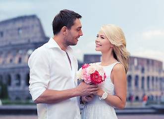 Image showing happy couple with bunch of flowers over coliseum