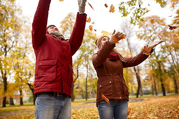 Image showing happy young couple throwing autumn leaves in park