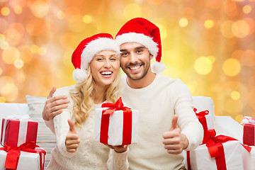 Image showing happy couple with christmas gifts and thumbs up