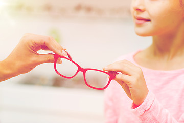 Image showing close up of girl taking glasses at optics store