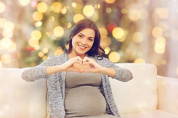 Image showing happy pregnant woman making heart gesture at home