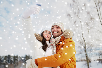 Image showing happy couple taking selfie by smartphone in winter